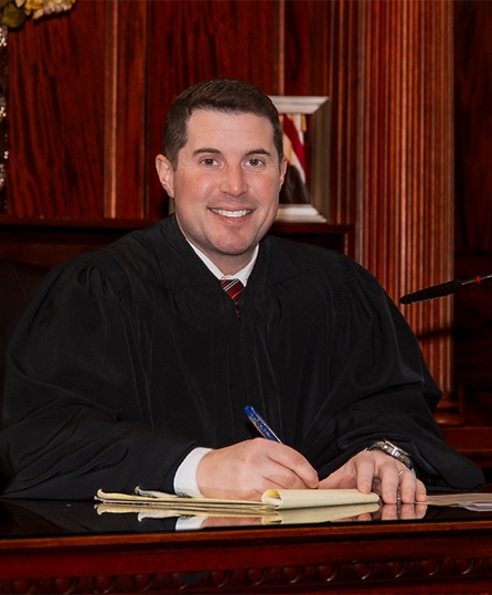 Judge Schimizzi wearing a judicial robe writing on a legal pad